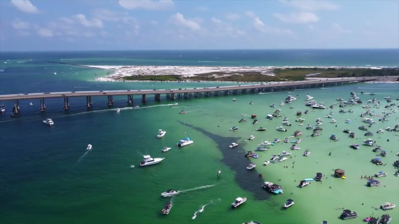 Aerial view of Crab Island sandbar with charter yachts anchored in emerald water